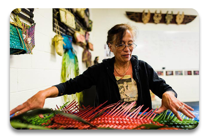 A woman spreading out her art piece that she created in her weaving course at Te Wananga o Aotearoa