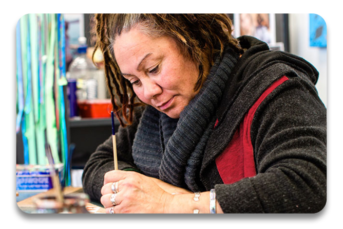 Tauira at a desk writing down ideas for inspiration in the Toi Maruata course