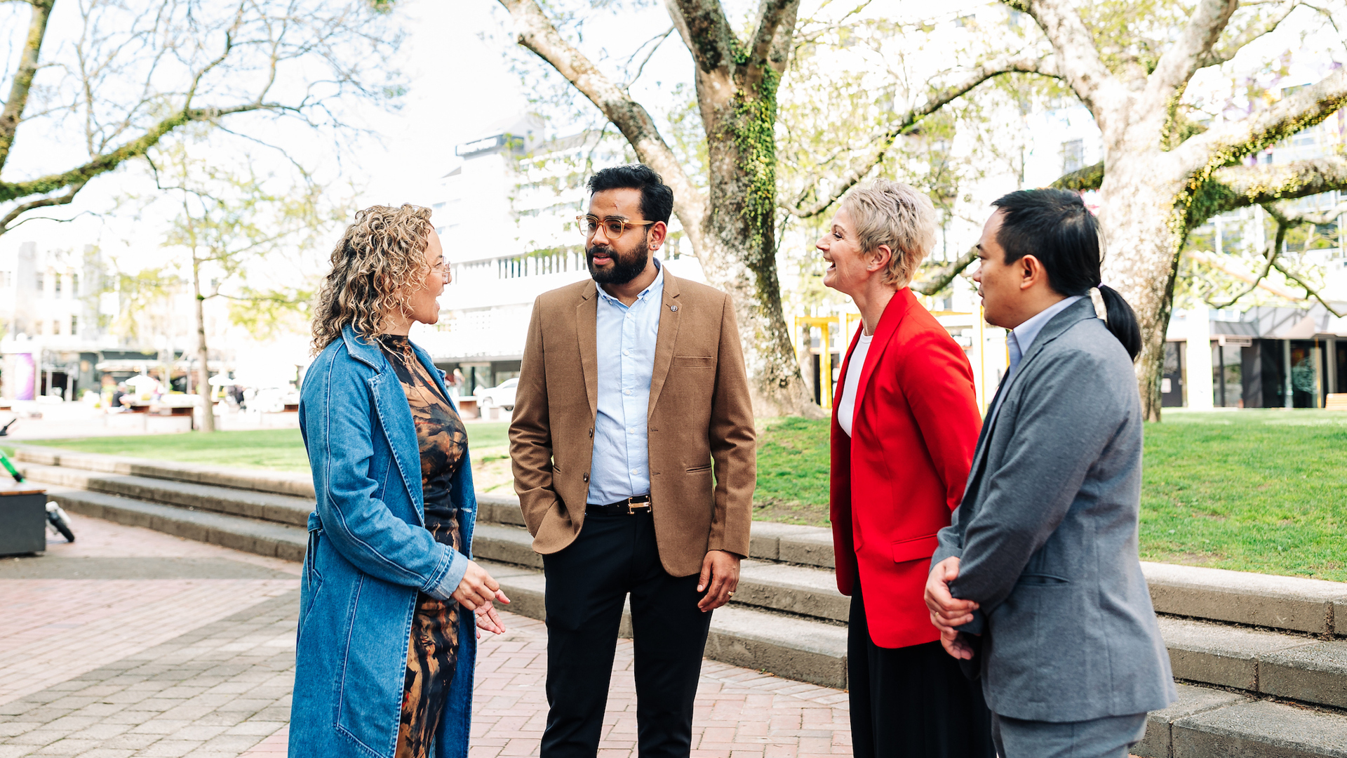 Four professionals talking in a city plaza