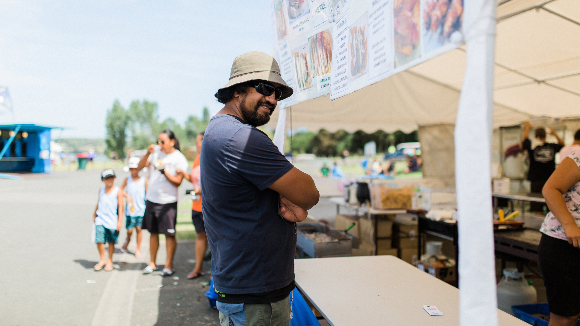 A casually dressed man in a bucket hat orders from a food stall