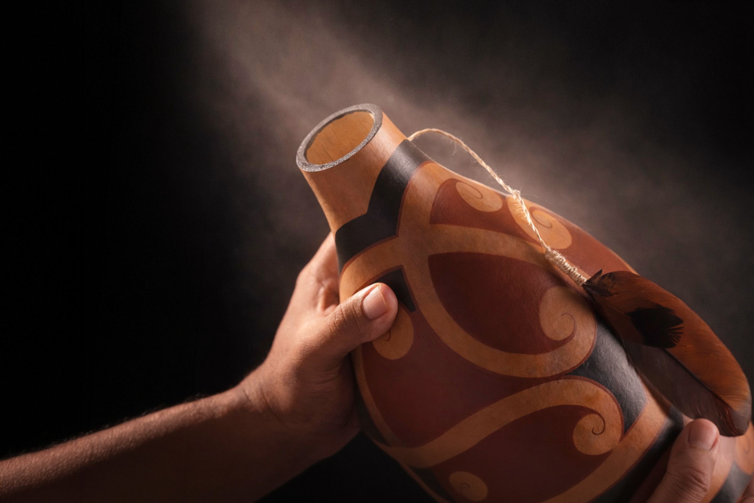 A pair of hands hold taonga puoro, a traditional Māori instrument created from a hue or gourd