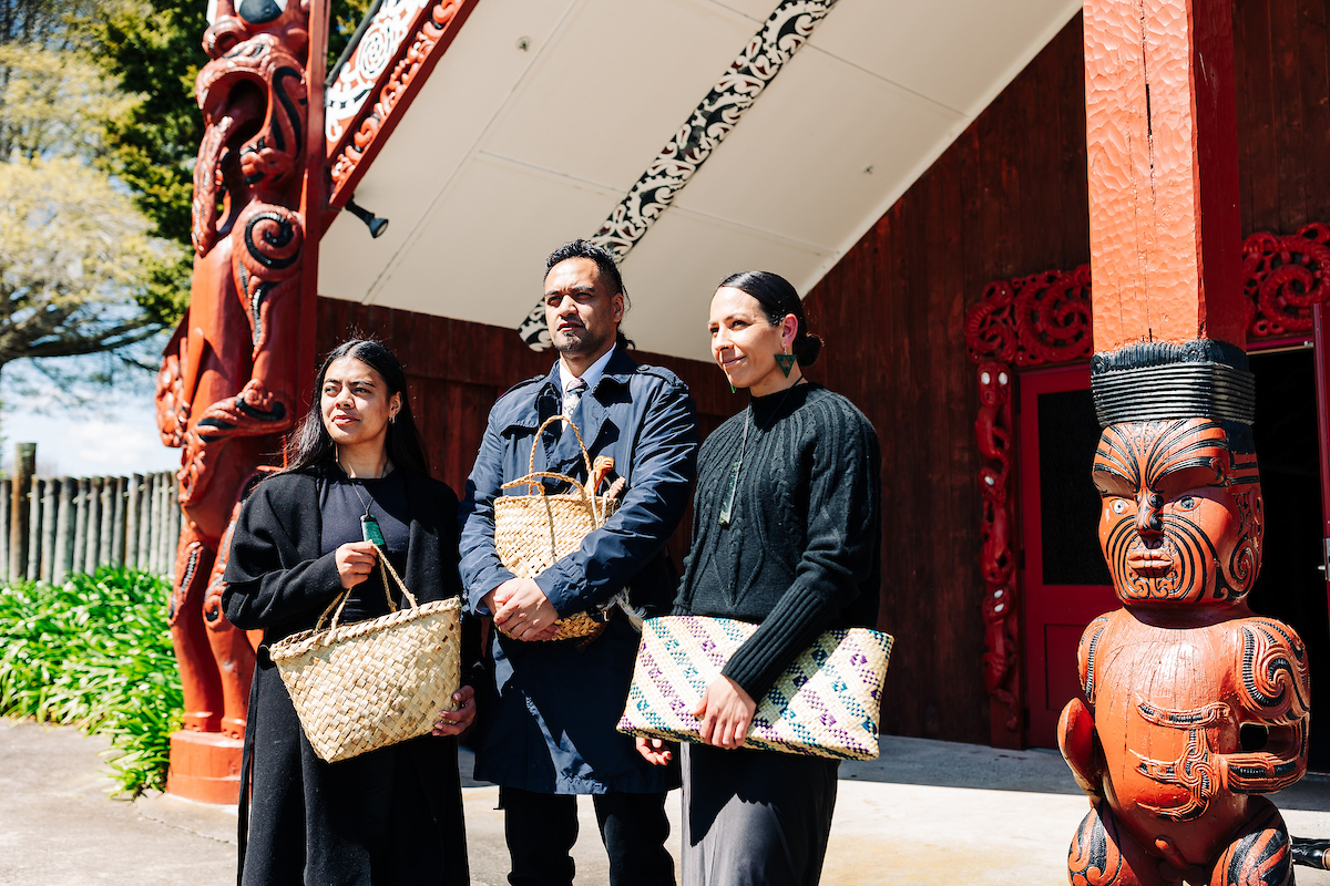 People holding kete outside the wharenui during a pōwhiri