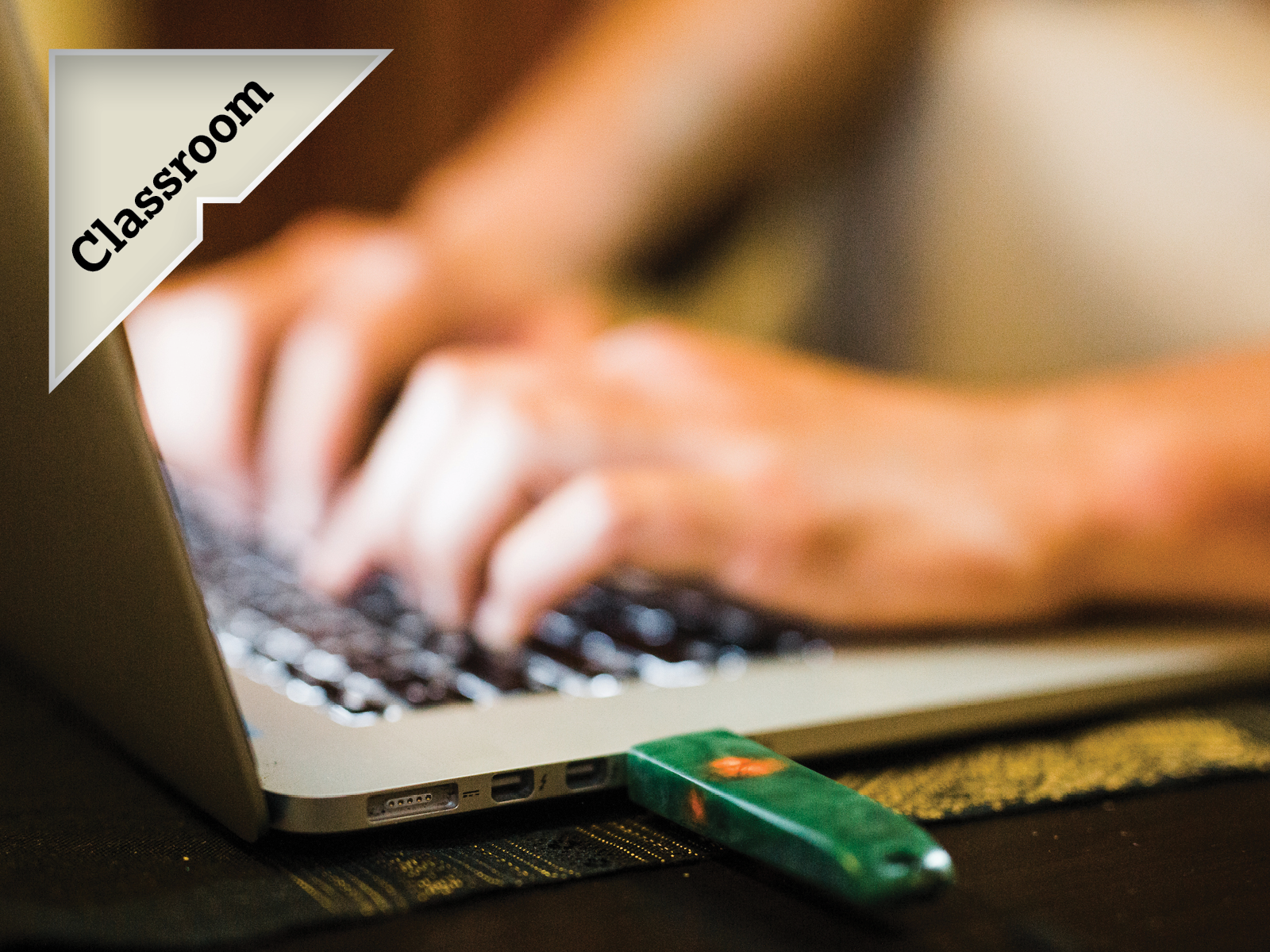 A pounamu USB in a laptop with hands typing and callout badge text 'Classroom'