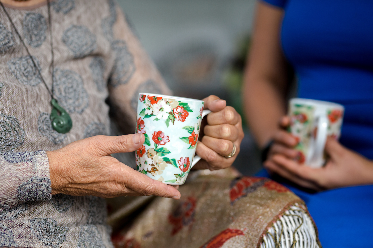 Two women sit together having a cup of tea