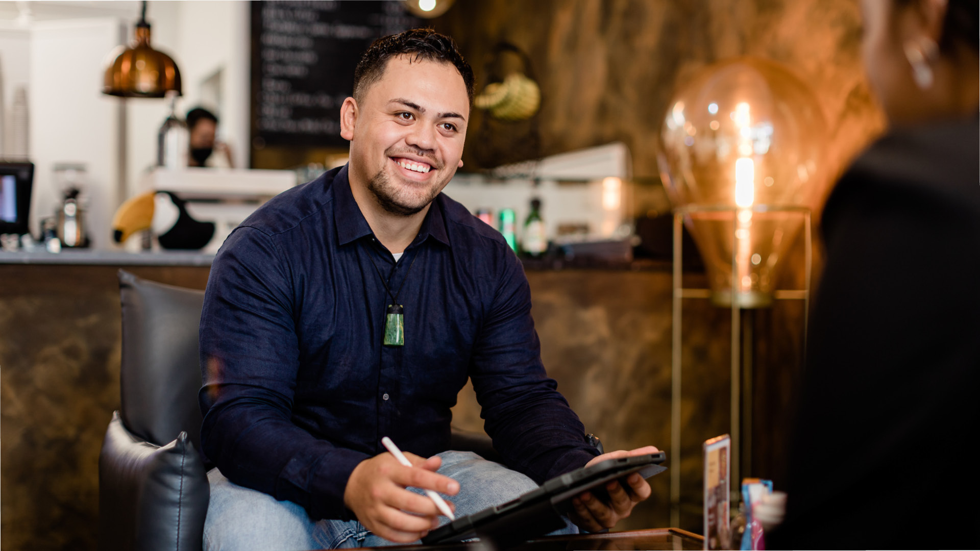 Te Wānanga o Aotearoa_Arahi Kaupapa_Certificate in Project Management Sub Image. Man sitting on chair in cafe with tablet