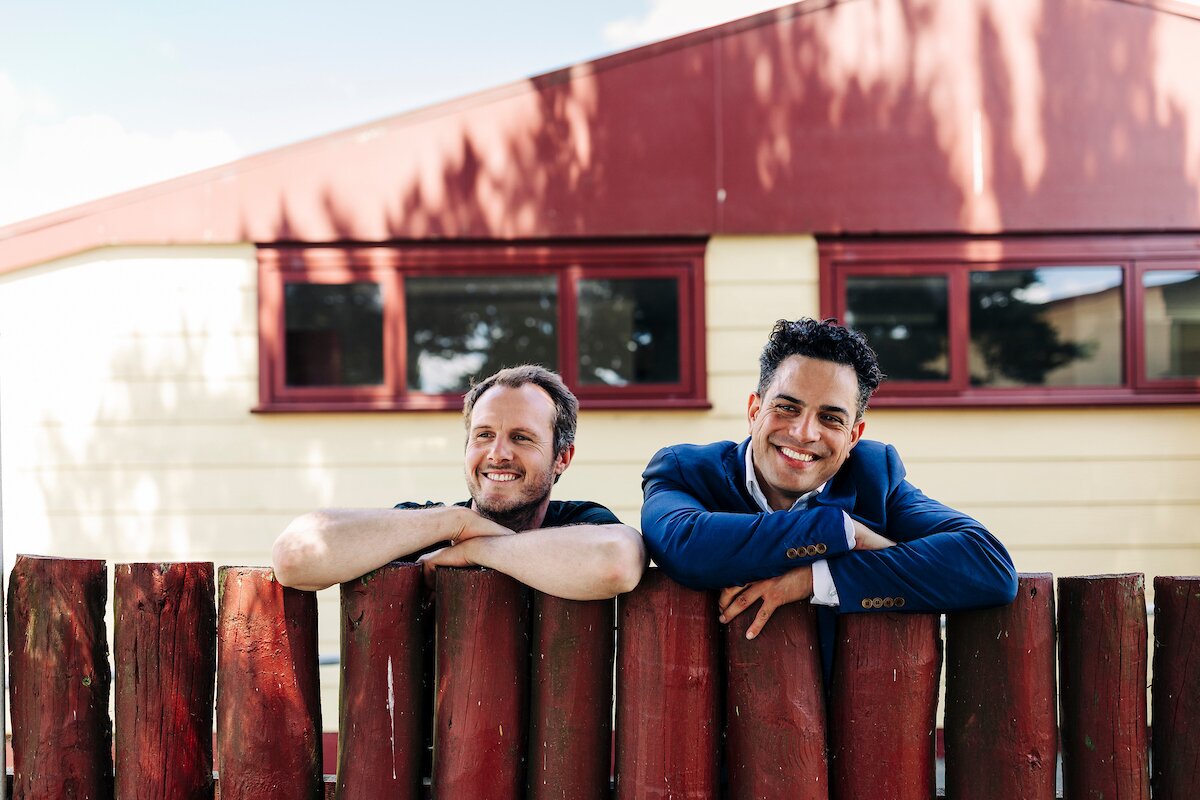 Two young men looking over wooden fence