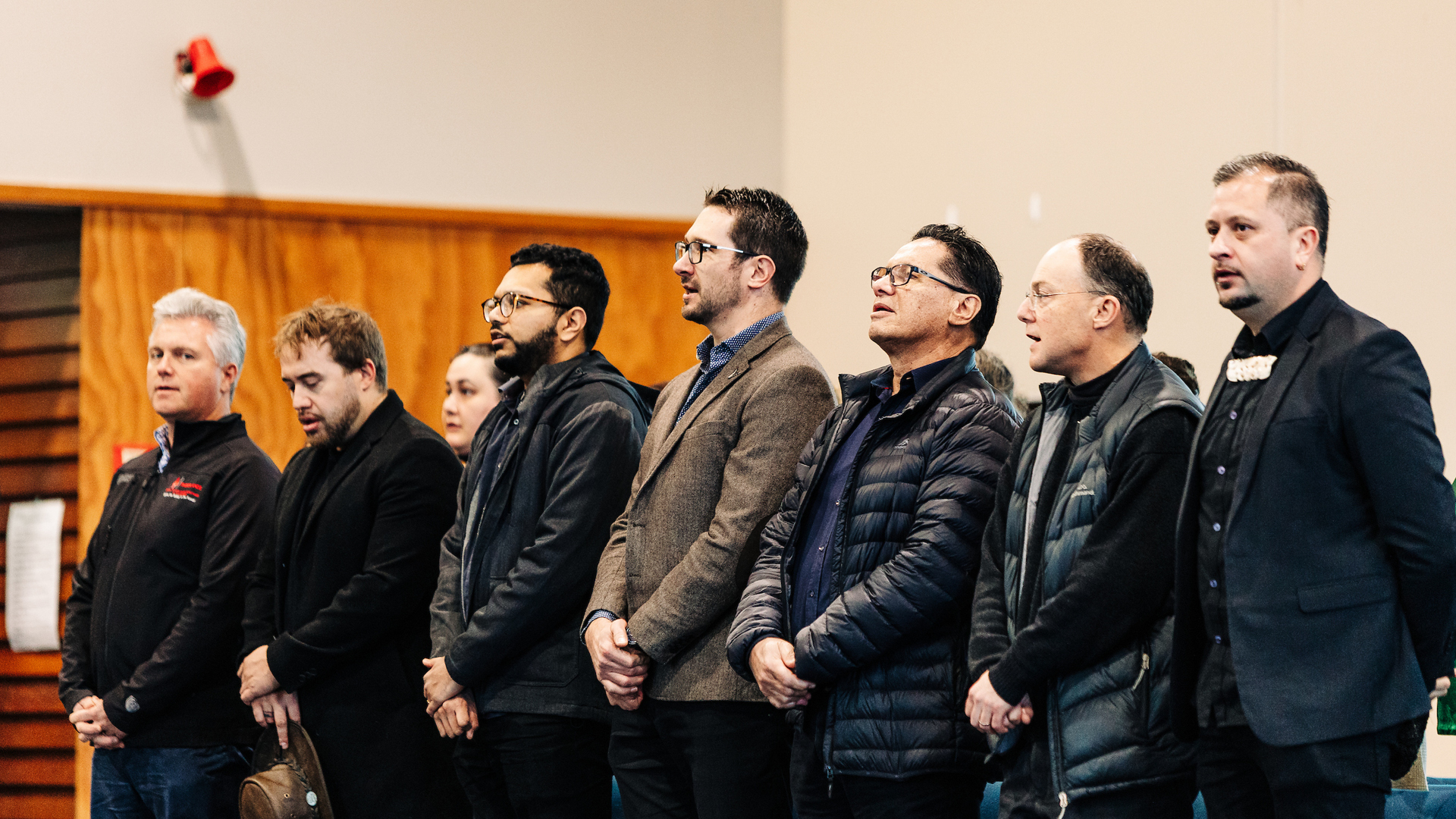 A group of men sing in the front row during a pōwhiri