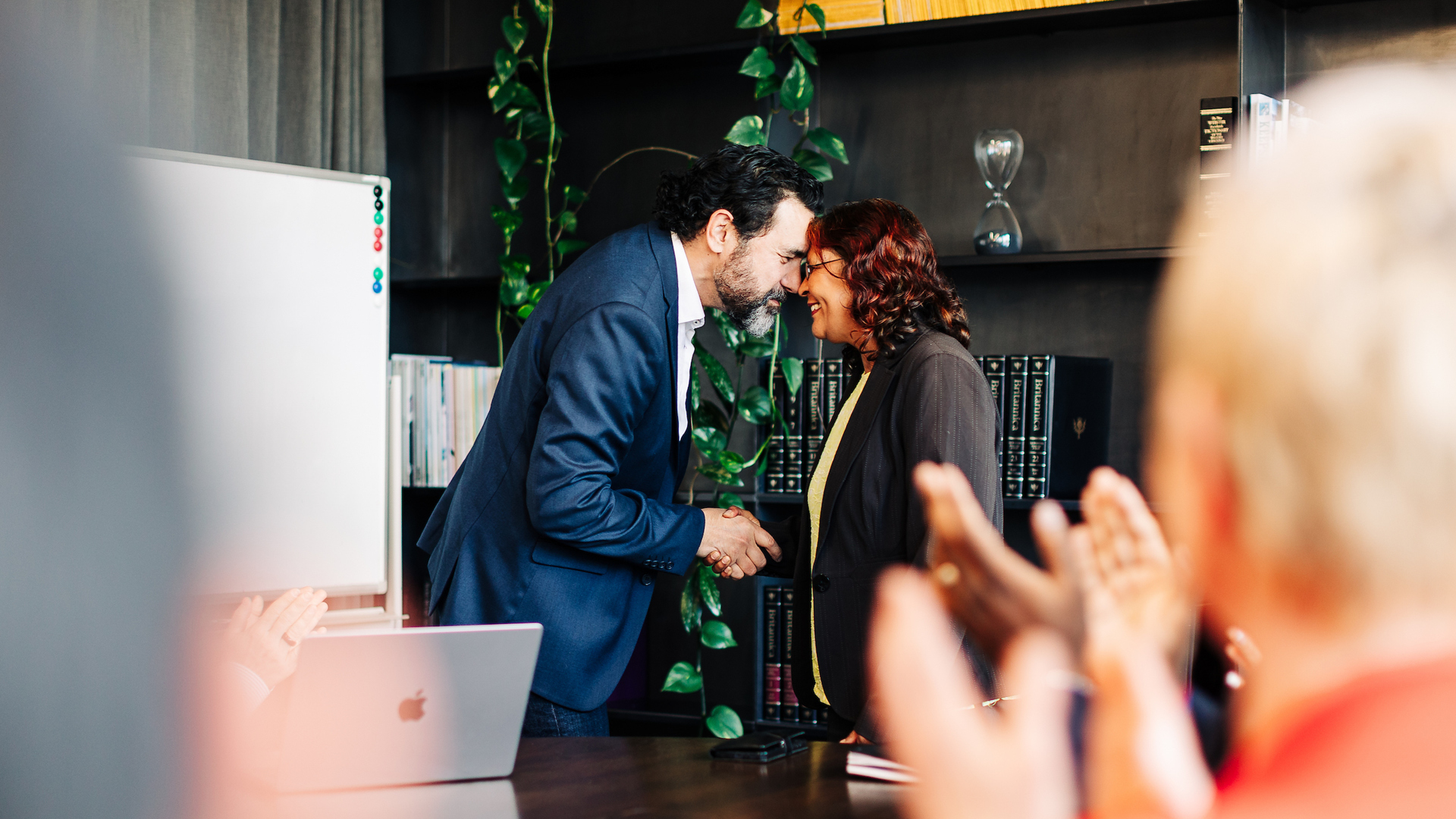 Two business professionals greet through hongi in a boardroom