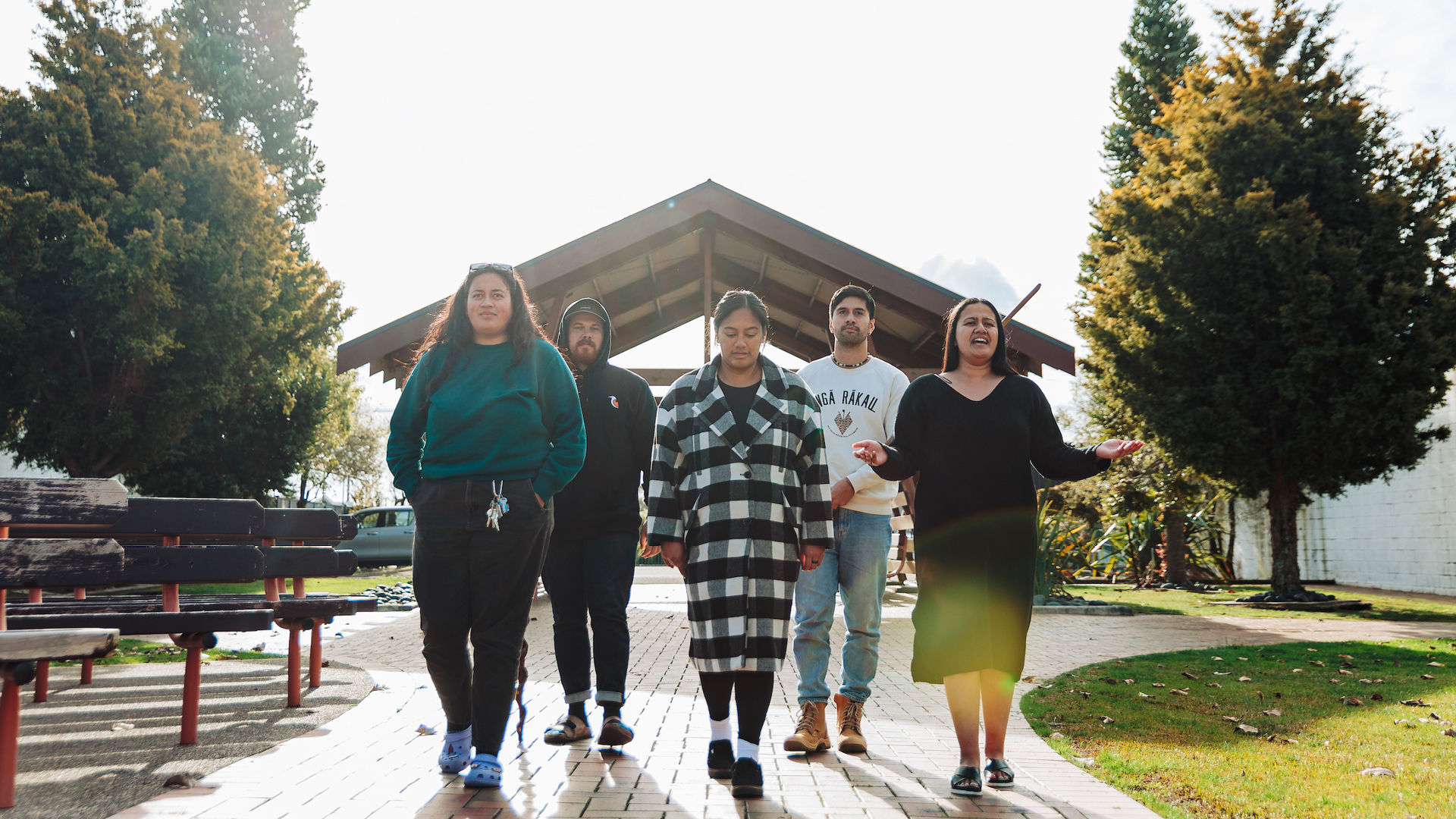 A woman leads a group of people onto the marae through the karanga
