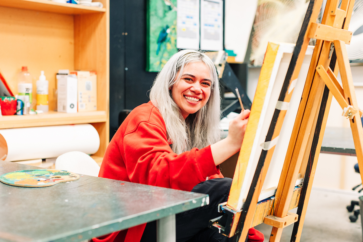 A Toi student paints on a canvas