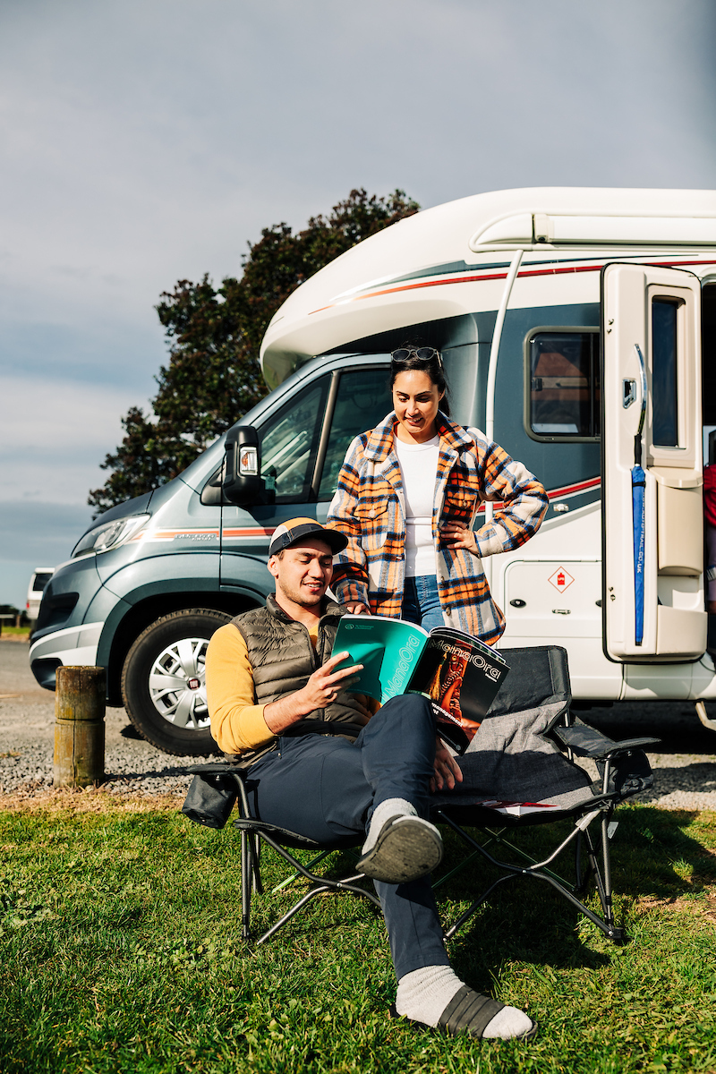 Two people studying te reo Māori while on holiday in their campervan