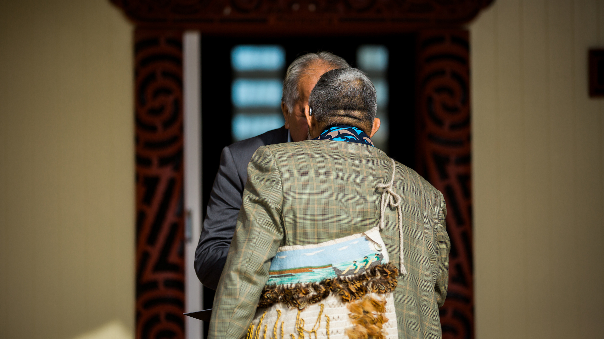 Two men hongi outside the wharenui during a graduation ceremony