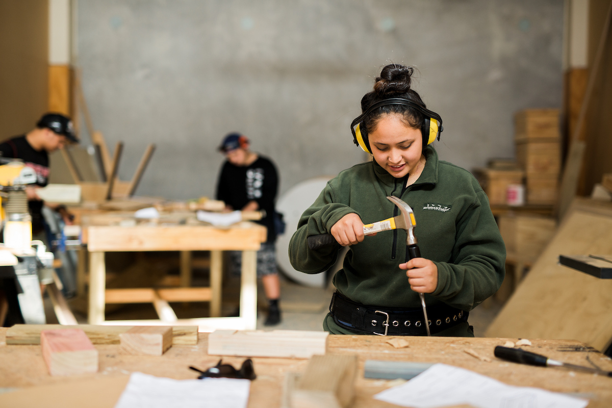 A whakairo student carves her project in the classroom