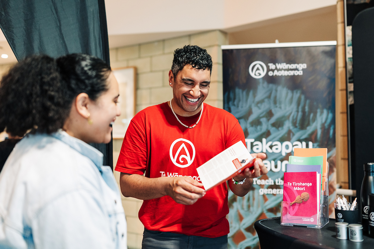 A kaimahi supports visitors at an event booth