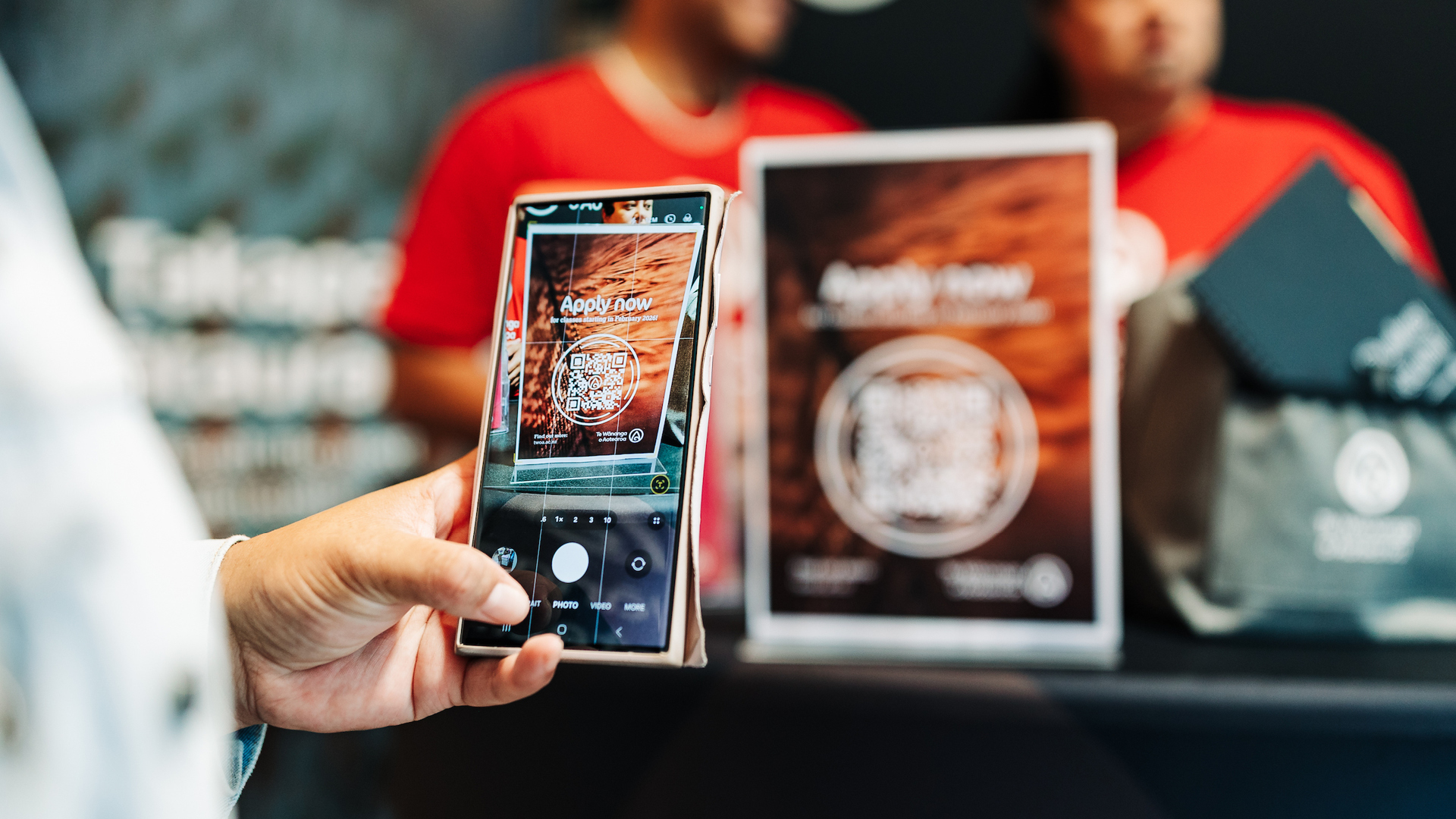 A booth visitor scans a QR code to enrol