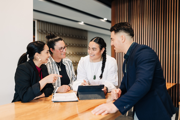 Four professionals talking around a board table