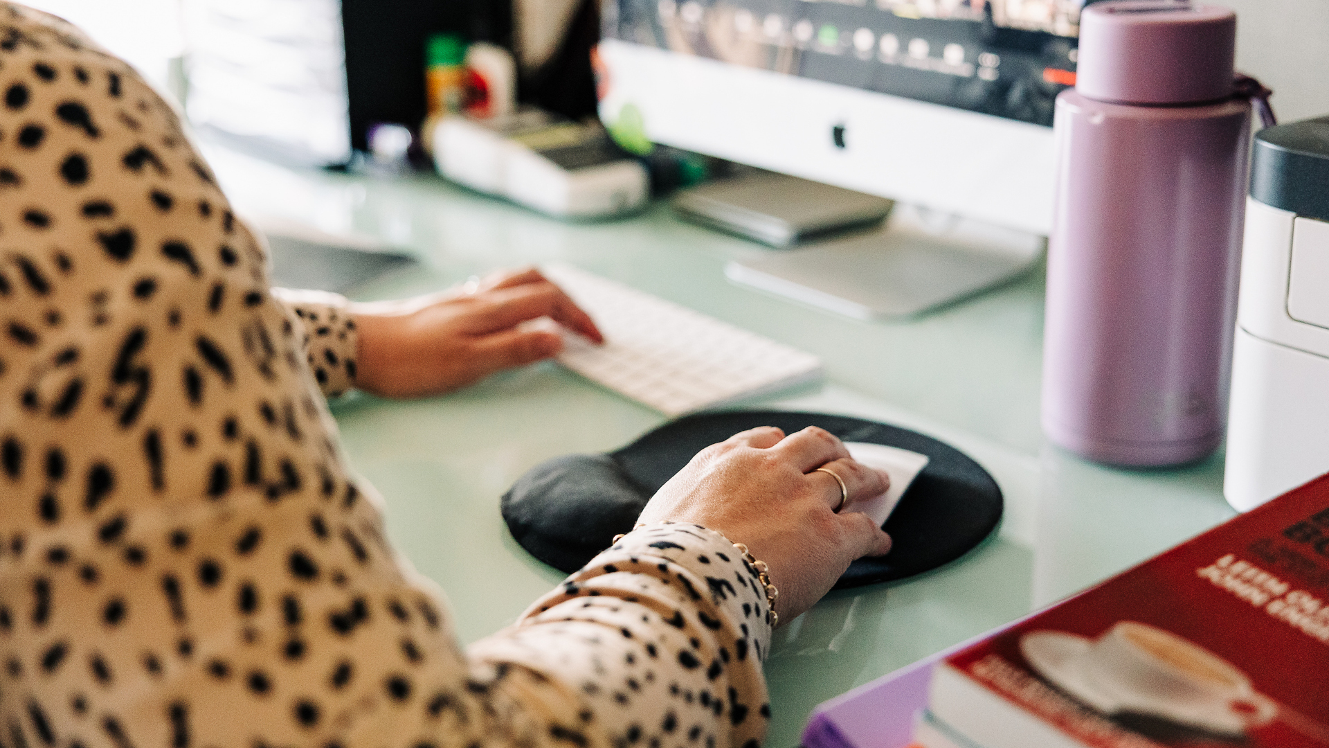 A person using their computer with a water bottle on the desk
