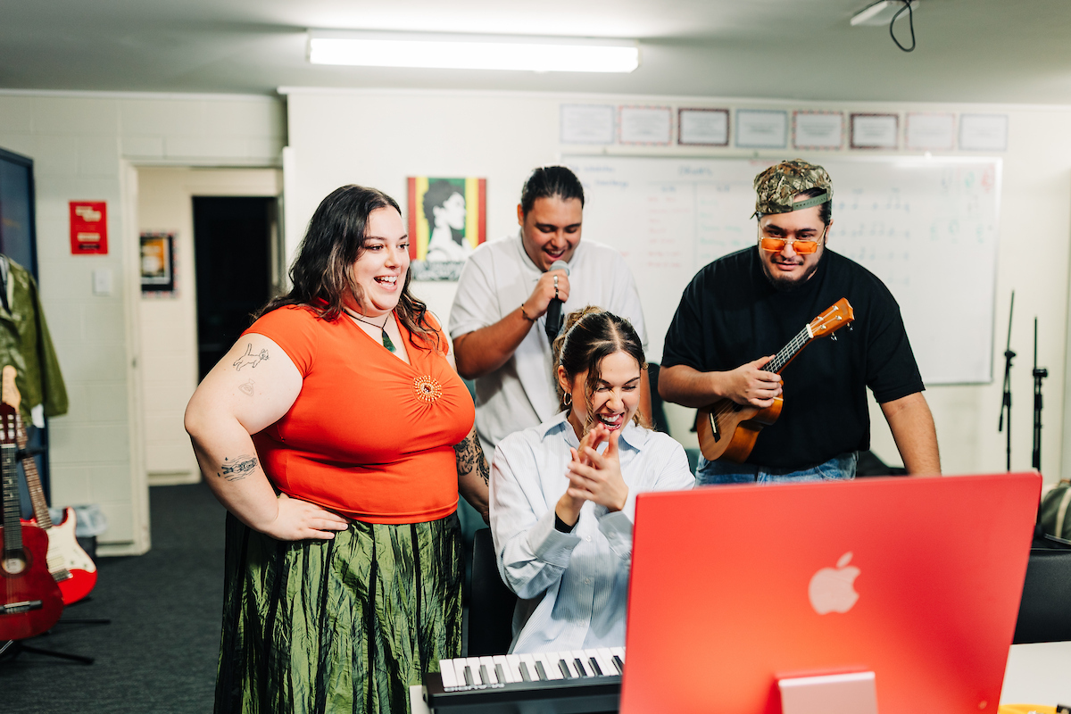 A group of Māori performing arts students edit music on a computer